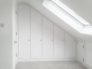 Loft Attic Wardrobe.Contemporary style sloping wardrobe fitted in the loft spare room. Another sample of fitted furniture created by our company is plain contemporary door wardrobe with cupboards and drawers along sloping ceiling. Good solution to fill dead space in your attic room.
