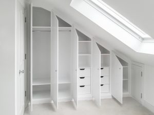 Loft Attic Wardrobe.Contemporary style sloping wardrobe fitted in the loft spare room. Another sample of fitted furniture created by our company is plain contemporary door wardrobe with cupboards and drawers along sloping ceiling. Good solution to fill dead space in your attic room.