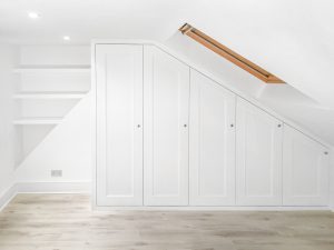 Traditional sloping wardrobe and floating shelves fitted in the loft spare room