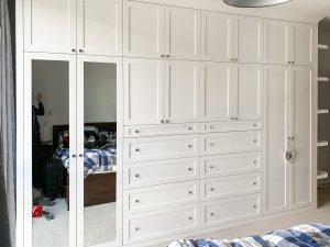 A huge 4 metres long wardrobe with LED lighting inside. Wooden cornice, drawers and recessed panels doors with metallic knobs