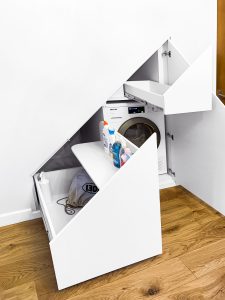 Under stairs cupboard with push-to-open door and door-drawer. Painted same colour as the wall so the cupboard seems hidden