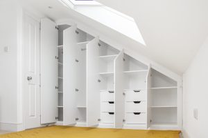 Loft Attic Wardrobe.Contemporary style sloping wardrobe fitted in the loft spare room. Another sample of fitted furniture created by our company is plain contemporary door wardrobe with cupboards and drawers along sloping ceiling. Good solution to fill dead space in your attic room.