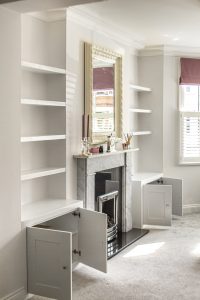 Alcove fitted TV cabinets with bookshelves besides the chimney