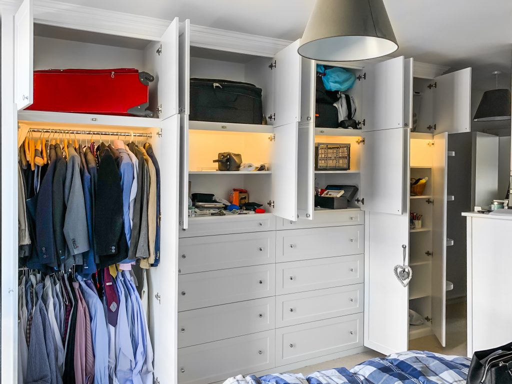 A huge 4 metres long wardrobe with LED lighting inside. Wooden cornice, drawers and recessed panels doors with metallic knobs