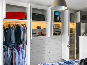A huge 4 metres long wardrobe with LED lighting inside. Wooden cornice, drawers and recessed panels doors with metallic knobs